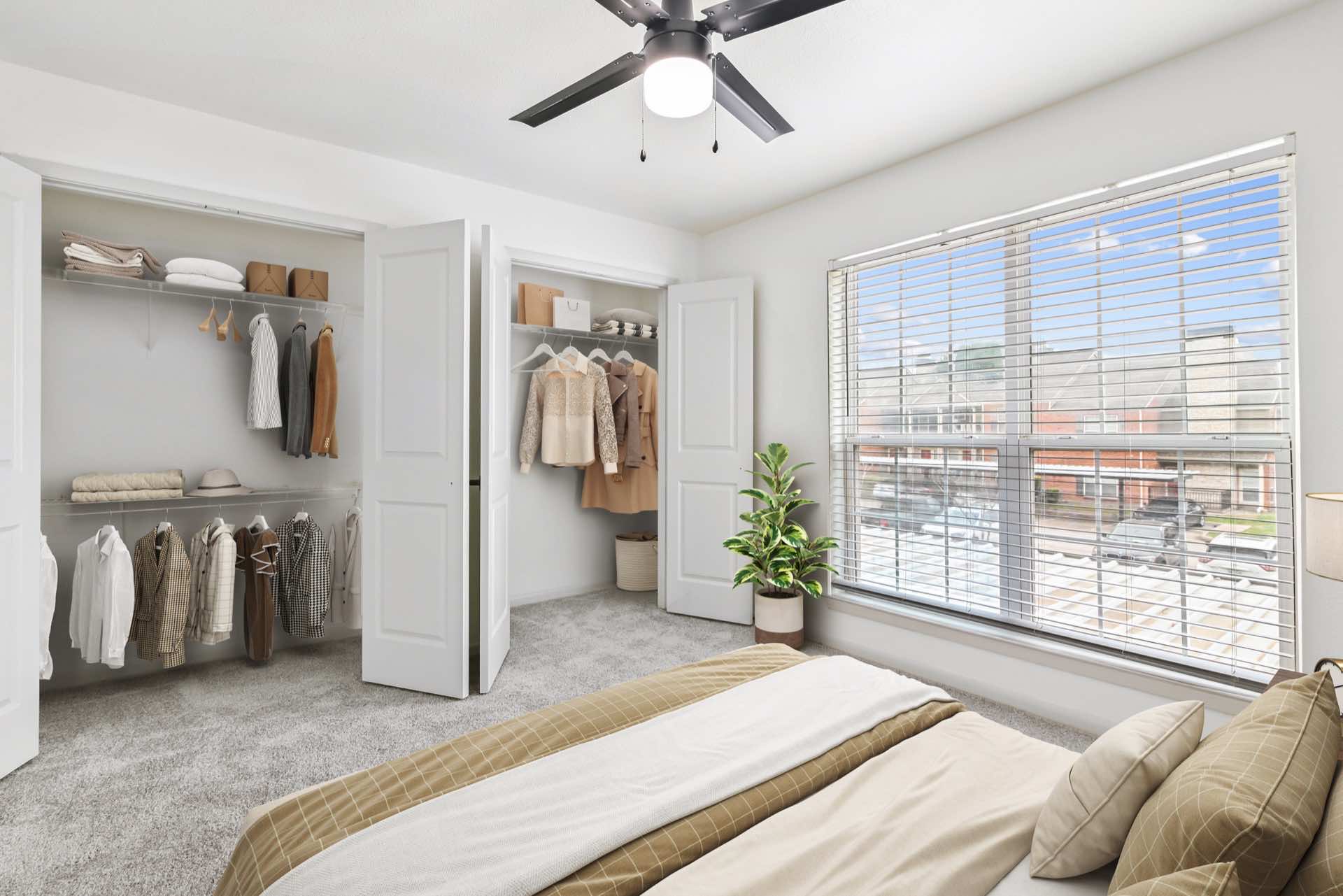 bedroom with large window, ceiling fan, and two reach-in closets